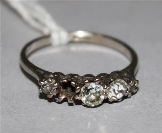 An 18ct white gold and graduated four (ex 5) stone diamond half hoop ring, size O.